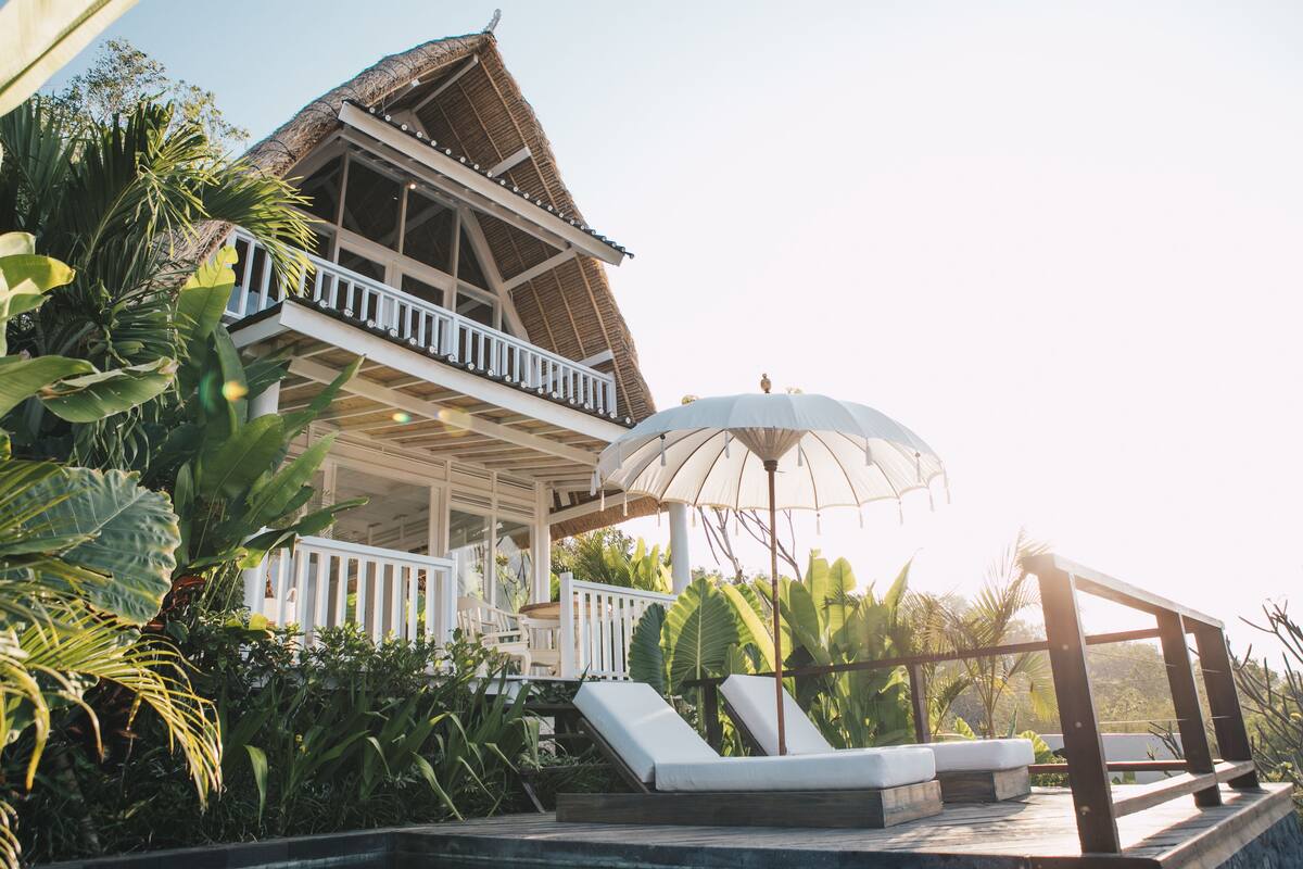 A resort with a pool, lounge chairs, and a thatched-roof building.
