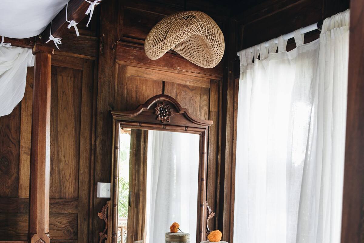 A wooden room with a bed, a vanity with a mirror, and a small table with decorative items.