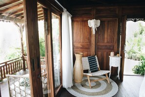 A wooden room with a wicker chair, a small white table, and a large woven basket. - White Tortoise Eco Villa's (Pecatu)