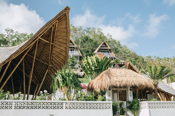 A resort with thatched-roof buildings, white lattice walls, and lush tropical vegetation. - White Tortoise Eco Villa's (Pecatu)