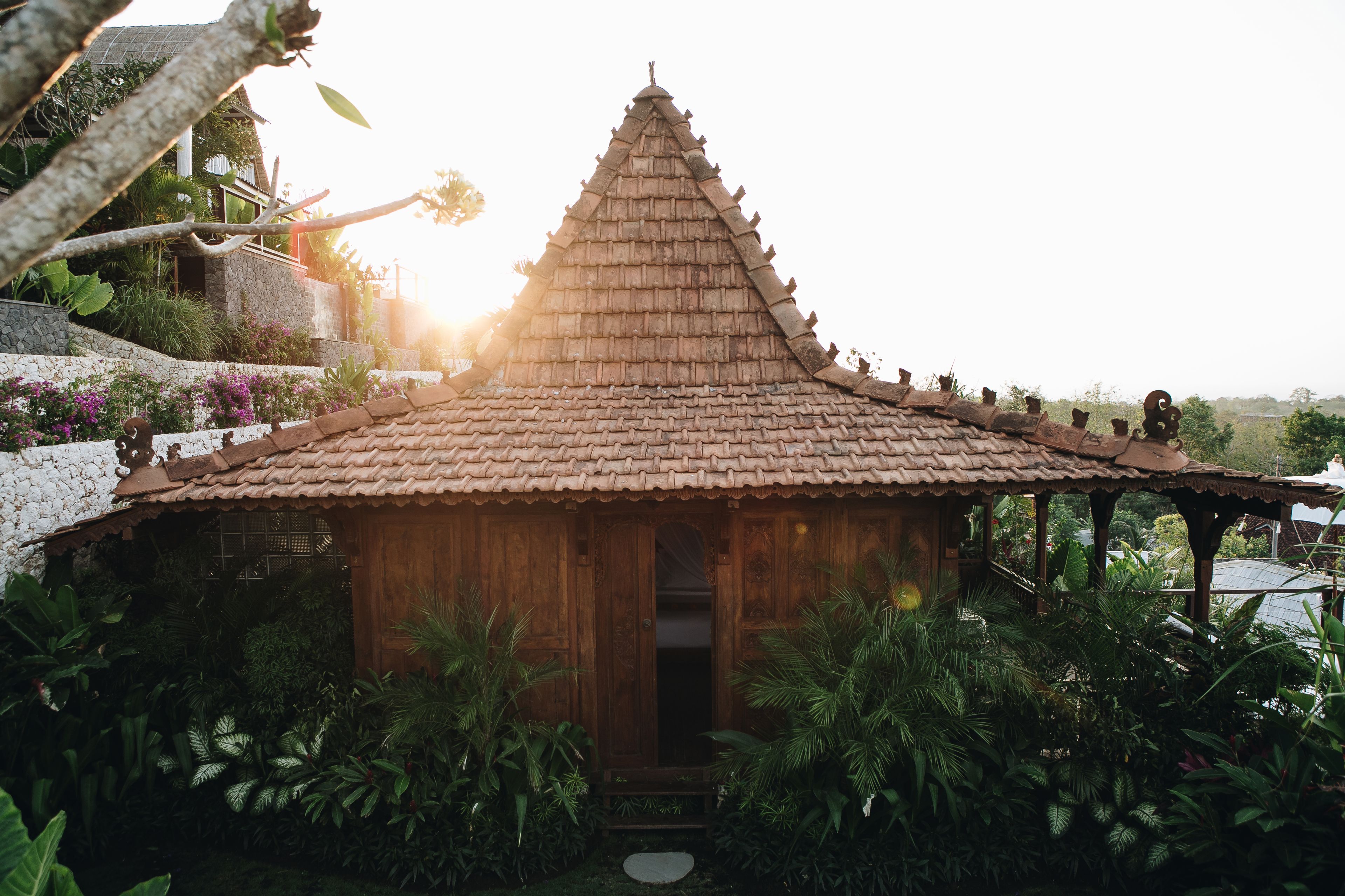 A small wooden structure with a tiled roof surrounded by lush greenery.