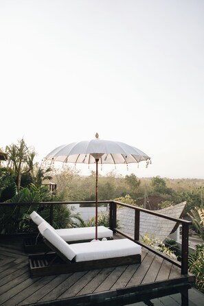 A wooden deck with two lounge chairs and a large umbrella. - White Tortoise Eco Villa's (Pecatu)