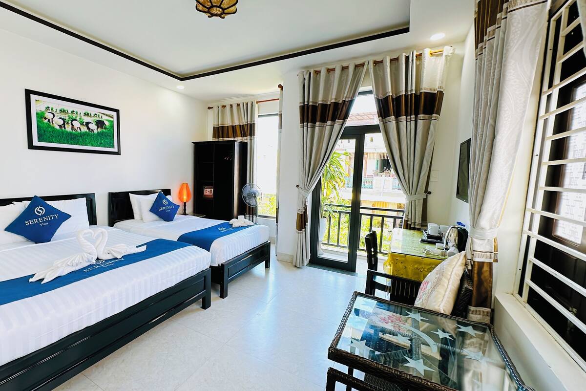 Une chambre d’hôtel avec deux lits, un balcon et un coin repas.