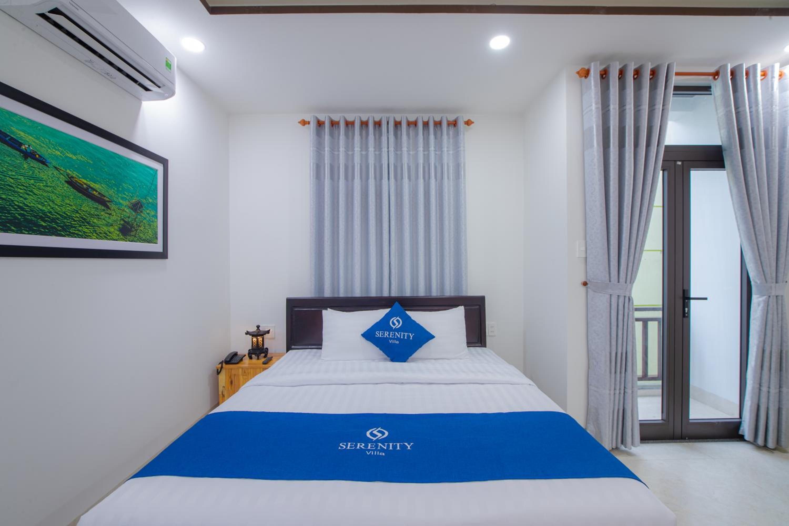 Een hotelkamer met een bed, nachtkastje, een lijst met foto aan de muur en een raam met gordijnen.