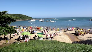 A crowded beach with numerous umbrellas and people enjoying the sunny weather. - Arm in arm in the heart of Morro Beach (Praia do Morro)