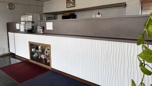A reception desk with a clock, a framed map, and a 'Nice' sign on the wall.