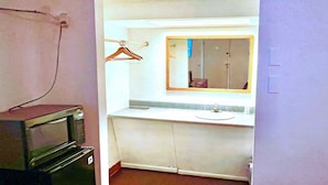 A small bathroom with a sink, mirror, and a microwave.