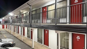 A motel with numbered rooms, a parking lot, and a covered walkway.