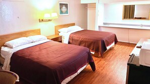 Une chambre d’hôtel avec deux lits, une table de chevet, un bureau avec une chaise, un miroir et une lampe fixée au mur.