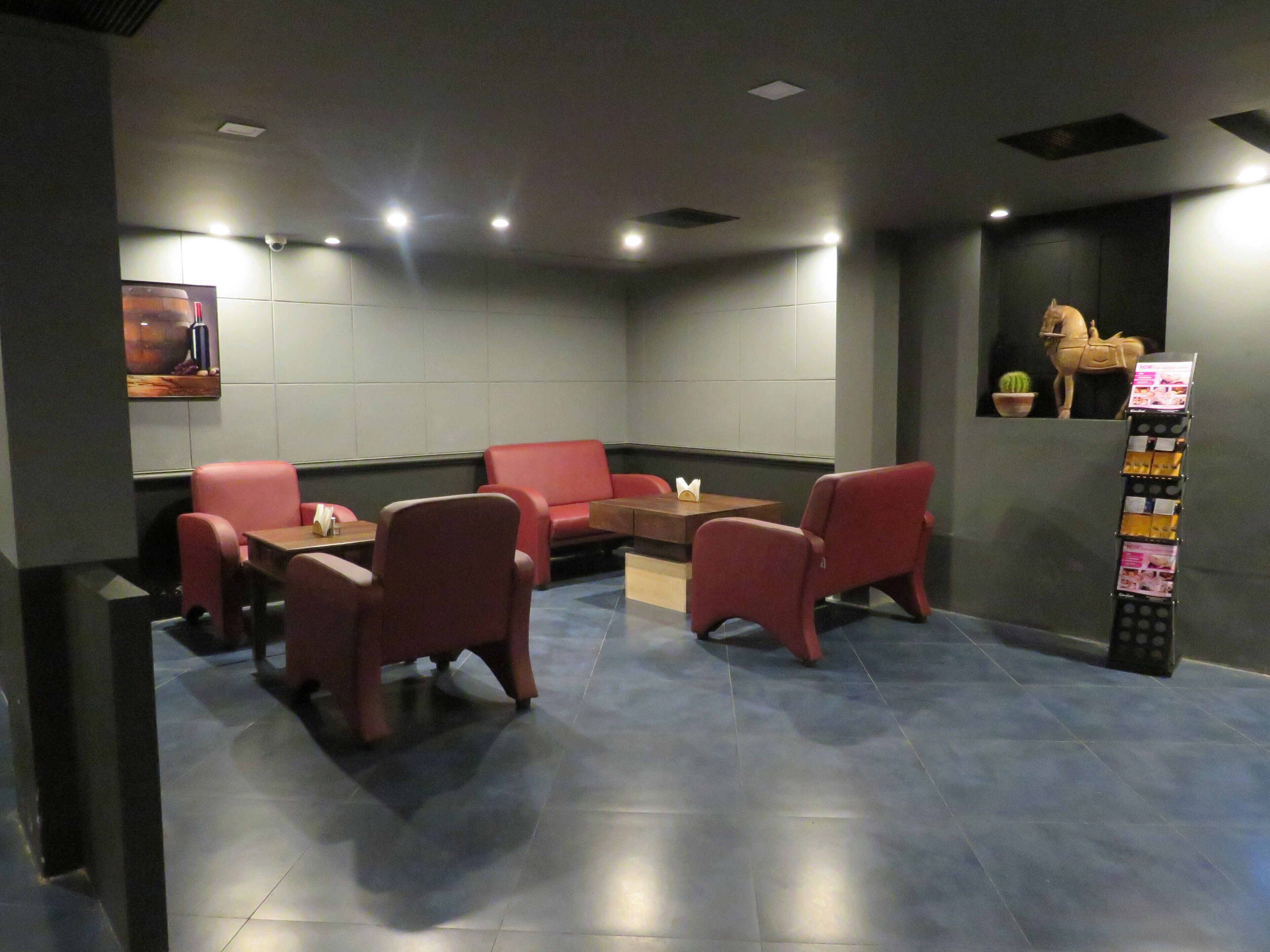 A modern lounge area with red seating, a wooden table, and a wall-mounted display.