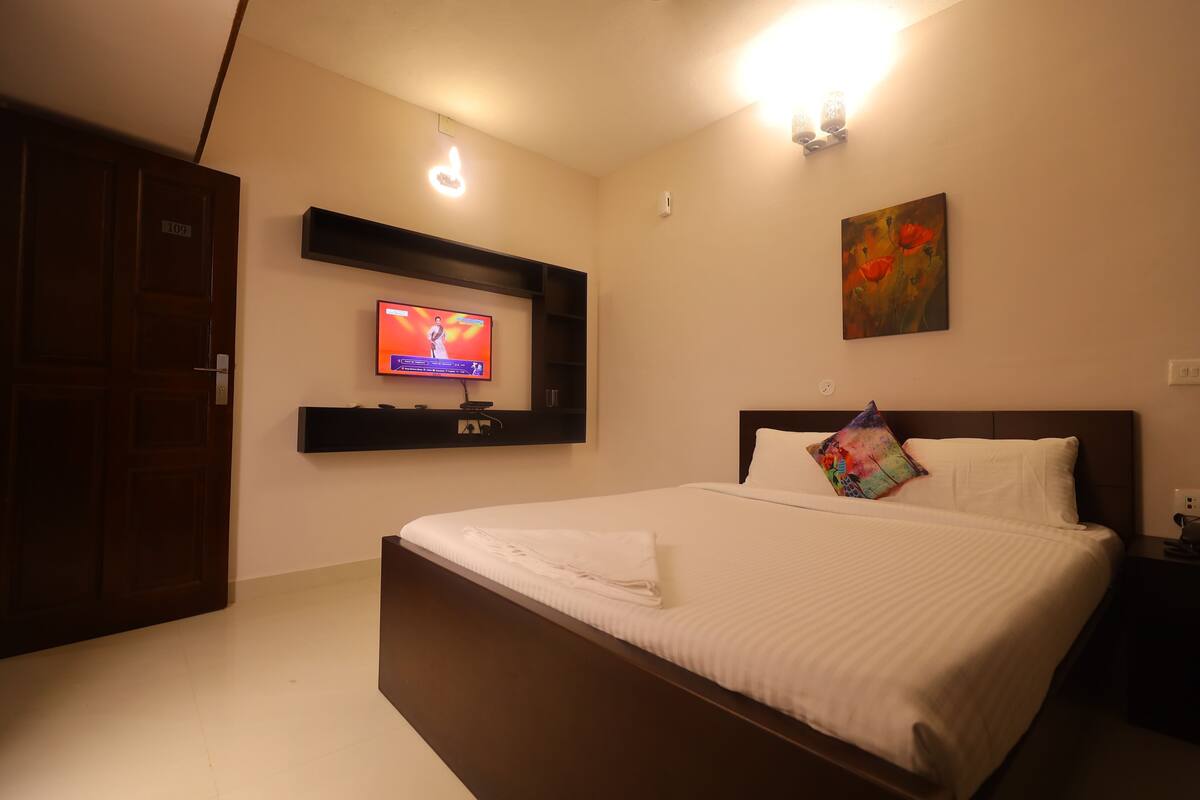 Een hotelkamer met een bed, een aan de muur bevestigde televisie, een schilderij en een deur.