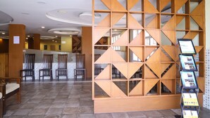 A lobby with a wooden partition, chairs, and a display rack with brochures. - Kfour Apartment & Hotels Private Limited (Madurai)