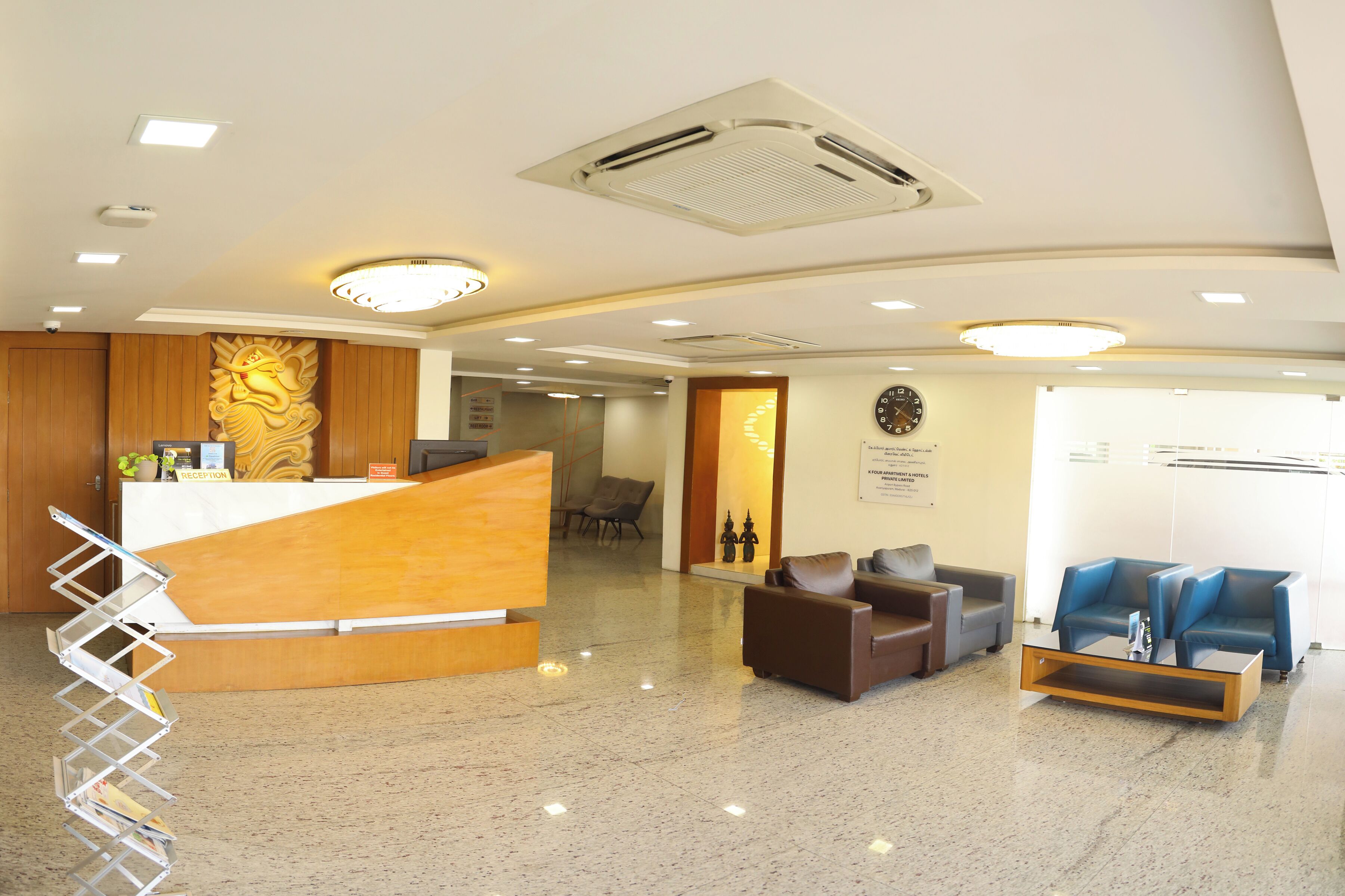A reception area with a wooden reception desk, seating area with leather chairs, a clock on the wall, and a spiral staircase.