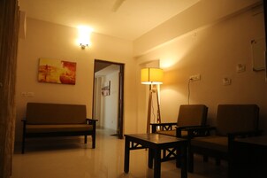 A living room with a sofa, two armchairs, a coffee table, a lamp, and a painting on the wall.