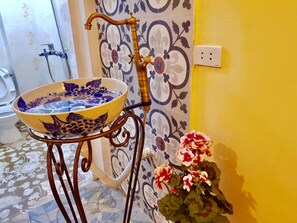A bathroom with a decorative sink on a metal stand, a shower, and a tiled floor.