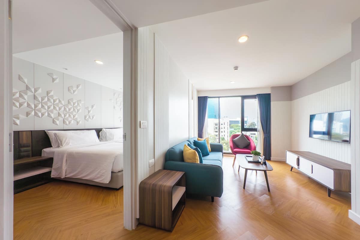Una habitación de hotel moderna con cama, sofá, mesa de centro y televisor.