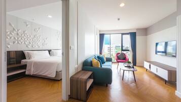 A modern hotel room with a bed, a sofa, a coffee table, and a TV.