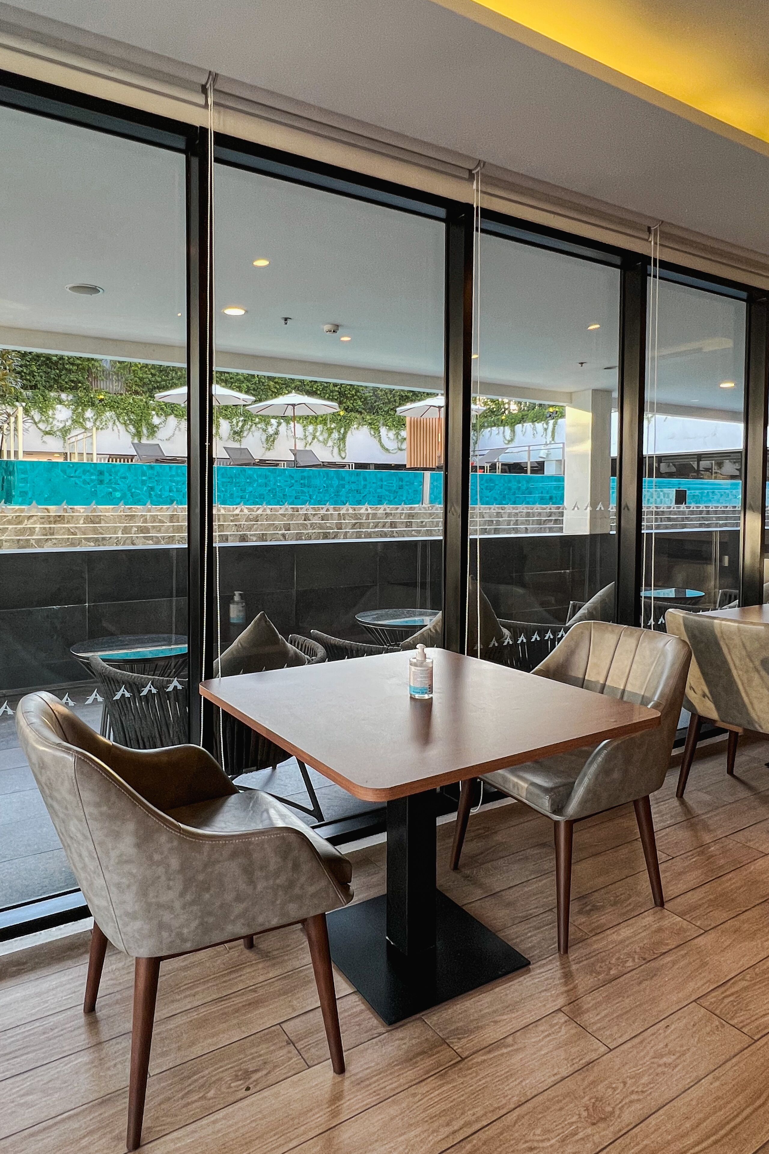 A modern dining area with a table and chairs, large windows, and a view of an outdoor pool area.