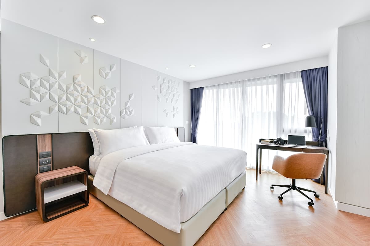 Una habitación de hotel moderna con una cama grande, un escritorio y una silla.
