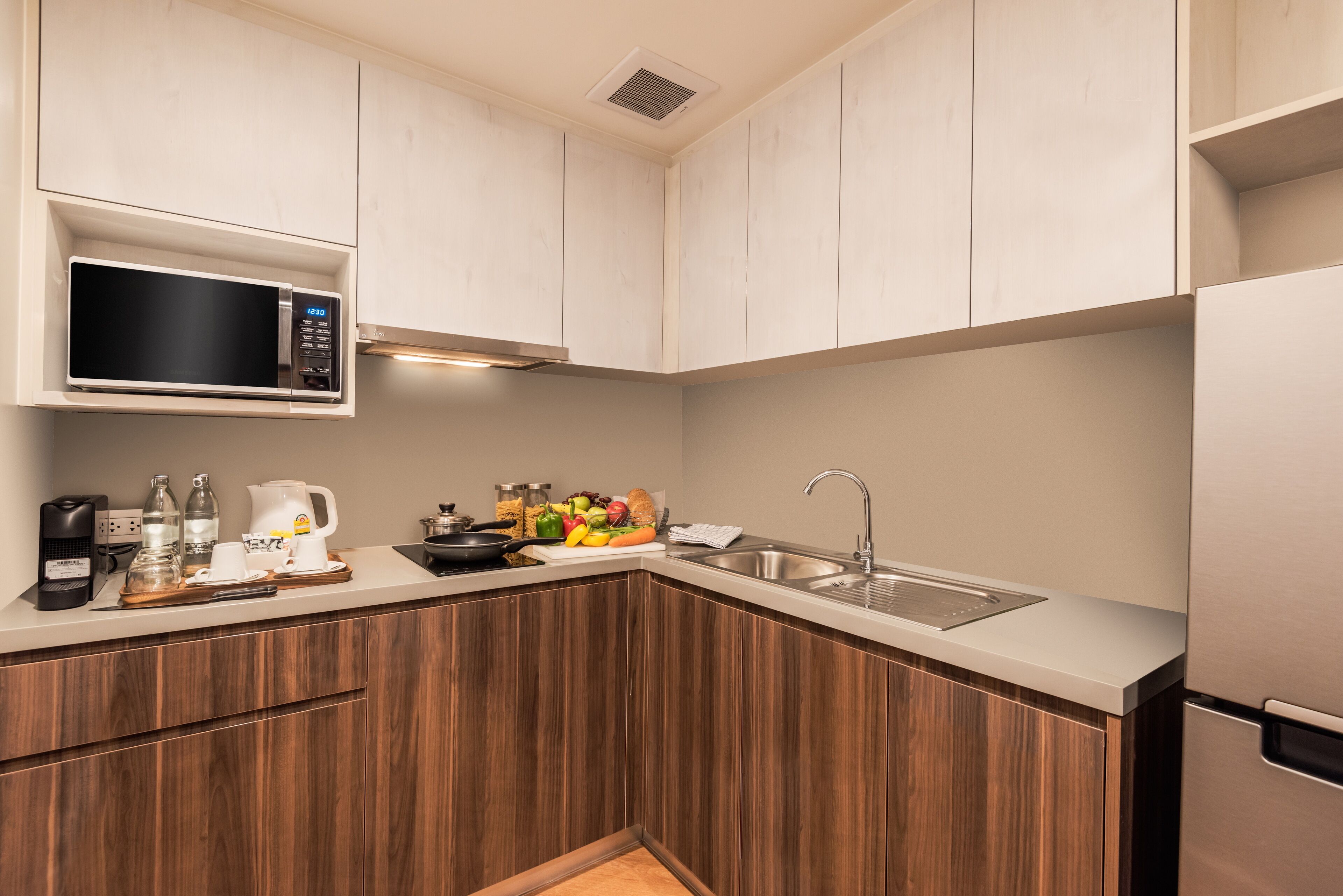 A modern kitchen with wooden cabinets, a built-in microwave, a sink, and a stainless steel refrigerator.