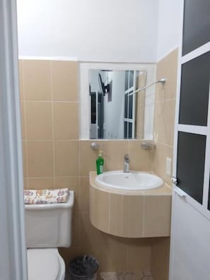 A small bathroom with a toilet, a sink, and a mirror. - Blue Hotel (Bacalar)