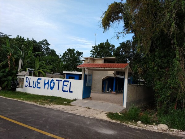 A hotel named Blue Hotel with a sign on a white wall, a covered entrance, and a red-tiled roof. - Blue Hotel (Bacalar)