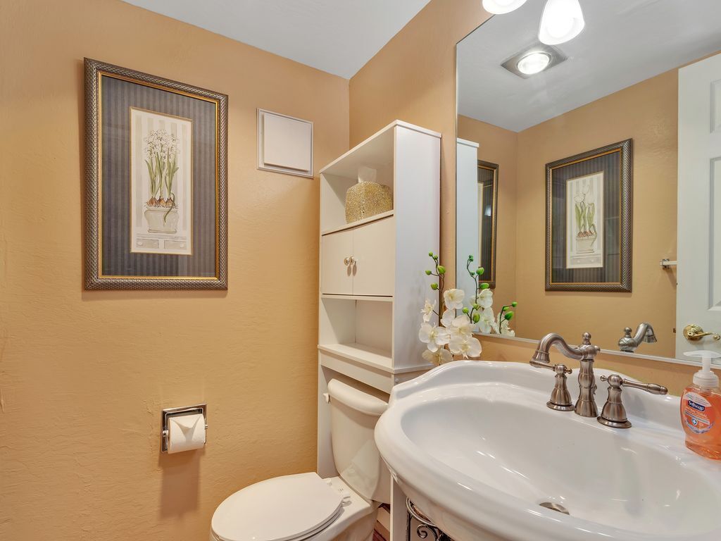 A bathroom with a toilet, sink, and shelves with toiletries.
