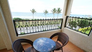 A balcony with a table and chairs, overlooking a beach with palm trees and the ocean. - Ji Li Ya Lan Homestay (Chenggong)