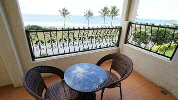 Enjoy the ocean view from this balcony with a round table and two wicker chairs.