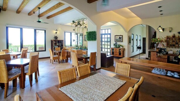 A spacious dining area with high ceilings and wooden beams, featuring multiple dining tables and chairs. - Ji Li Ya Lan Homestay (Chenggong)