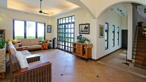 A spacious living room with a sofa, a coffee table, and a fireplace. There is a large window and a door leading to another room. - Ji Li Ya Lan Homestay (Chenggong)