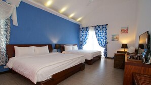 A hotel room with two beds, a wooden desk, a mirror, and a window with blue curtains. - Ji Li Ya Lan Homestay (Chenggong)