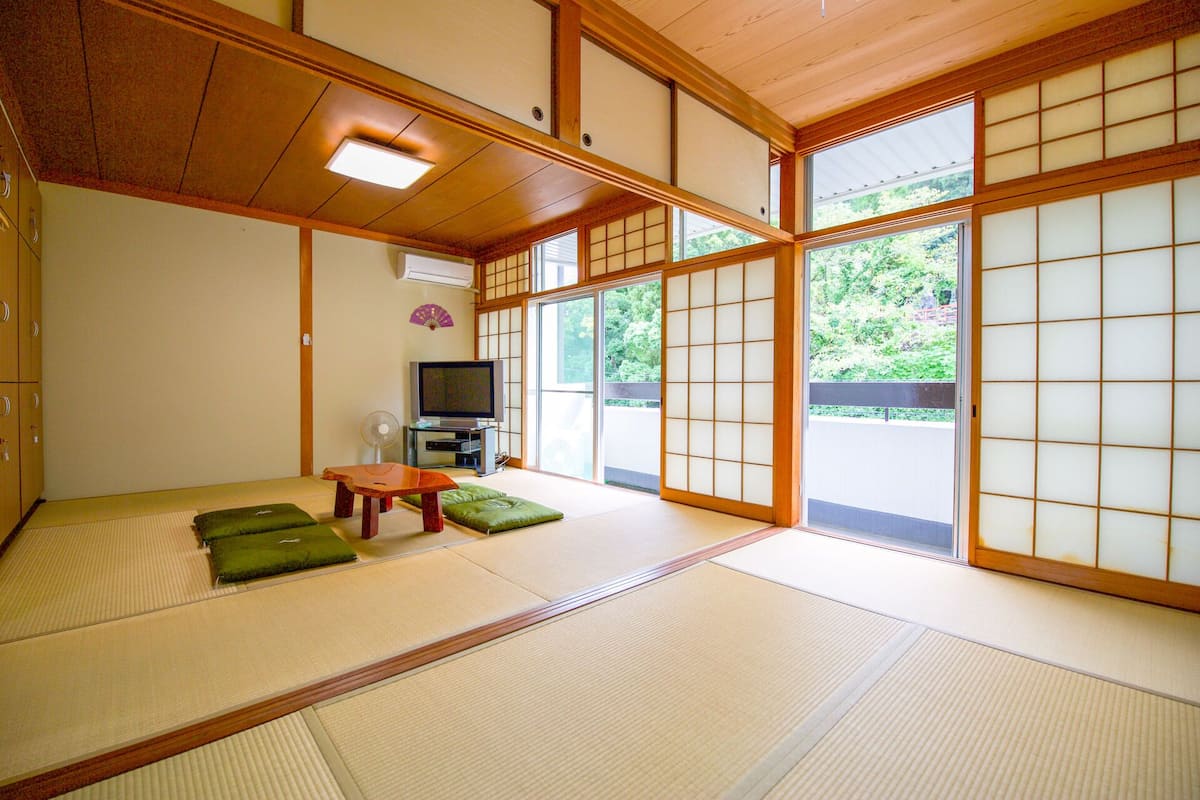A traditional Japanese room with tatami flooring, a television, and sliding doors.