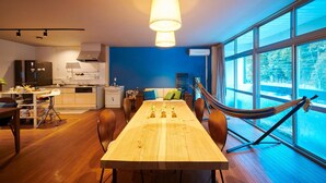 A modern kitchen with a dining area, large windows, and a hammock. - Hostel Coliberty (Tokushima)