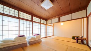 A traditional Japanese room with tatami flooring, a futon bed, and sliding shoji doors. - Hostel Coliberty (Tokushima)