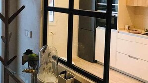 Una cocina moderna con armarios blancos, un refrigerador negro y un espacio de vidrio con una planta.