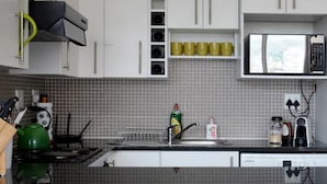 Eine moderne Küche mit weißen Schränken, einem Edelstahlkühlschrank, einer Mikrowelle und einem Spülbecken.