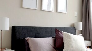 Ein Hotelzimmer mit einem Bett, Nachttischlampen, einem Nachttisch und einem Fenster mit Blick auf die Stadt.