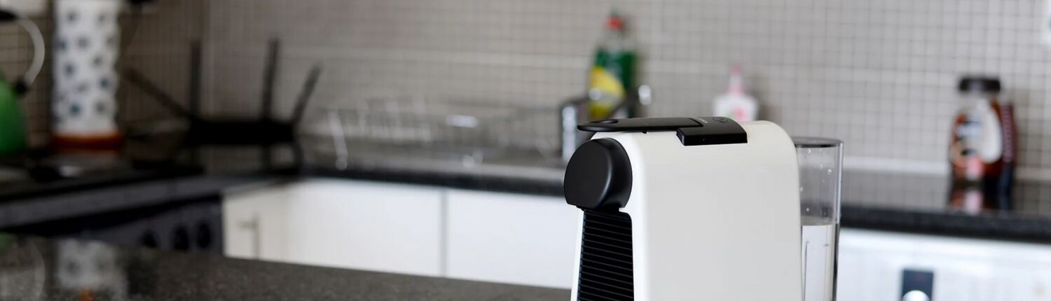 Una cocina con diseño moderno, que presenta un electrodoméstico blanco con asa negra, un lavamanos de acero inoxidable y un salpicadero de azulejos.