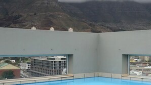 Ein Poolbereich mit Blick auf eine Stadtlandschaft und Berge im Hintergrund.