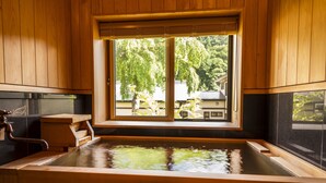 A wooden bathtub with a view of a house and trees outside. - Yukemuri no yado Inazumi onsen (Yuzawa)