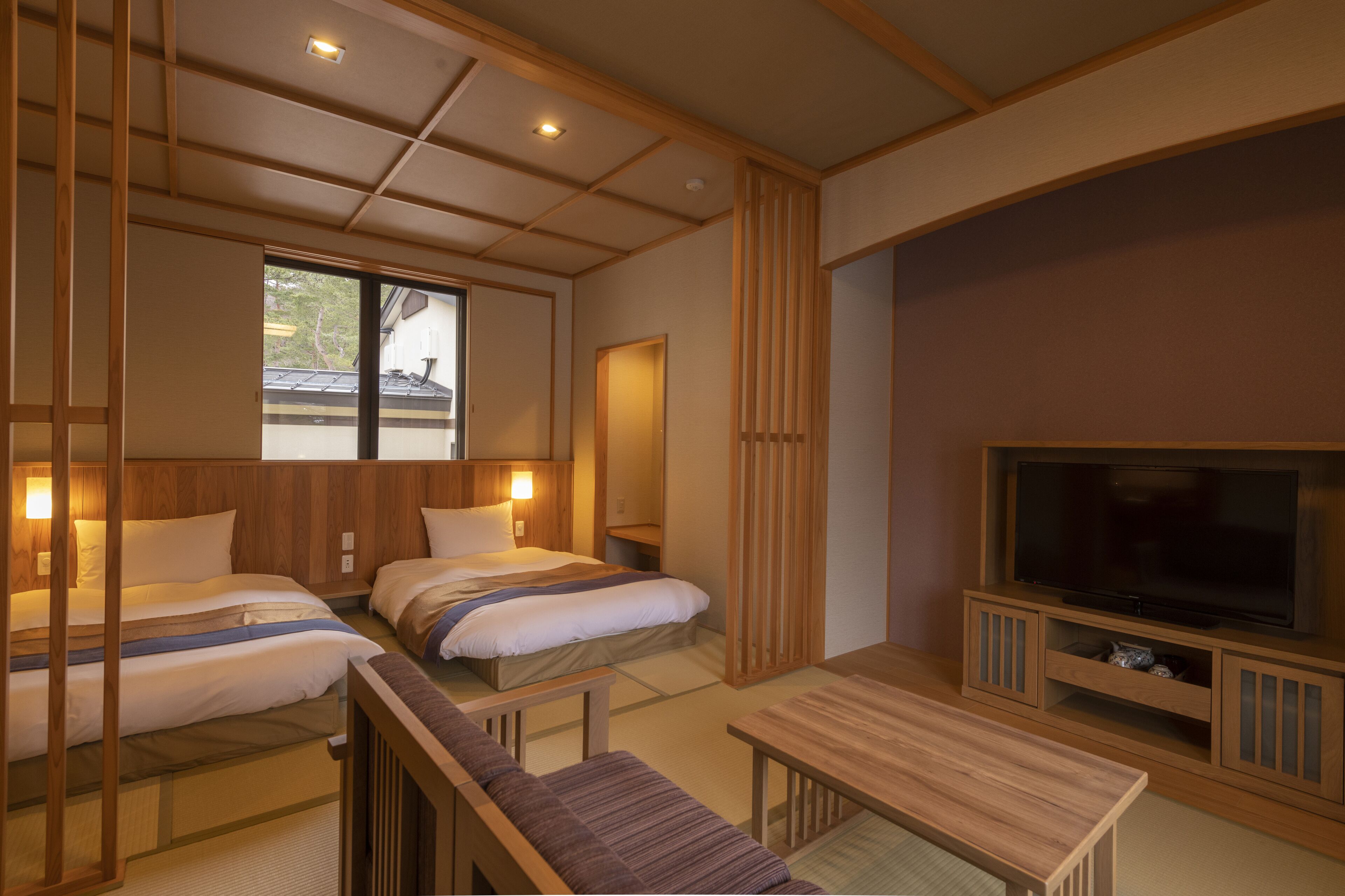 A hotel room with two beds, a TV, and a wooden table.