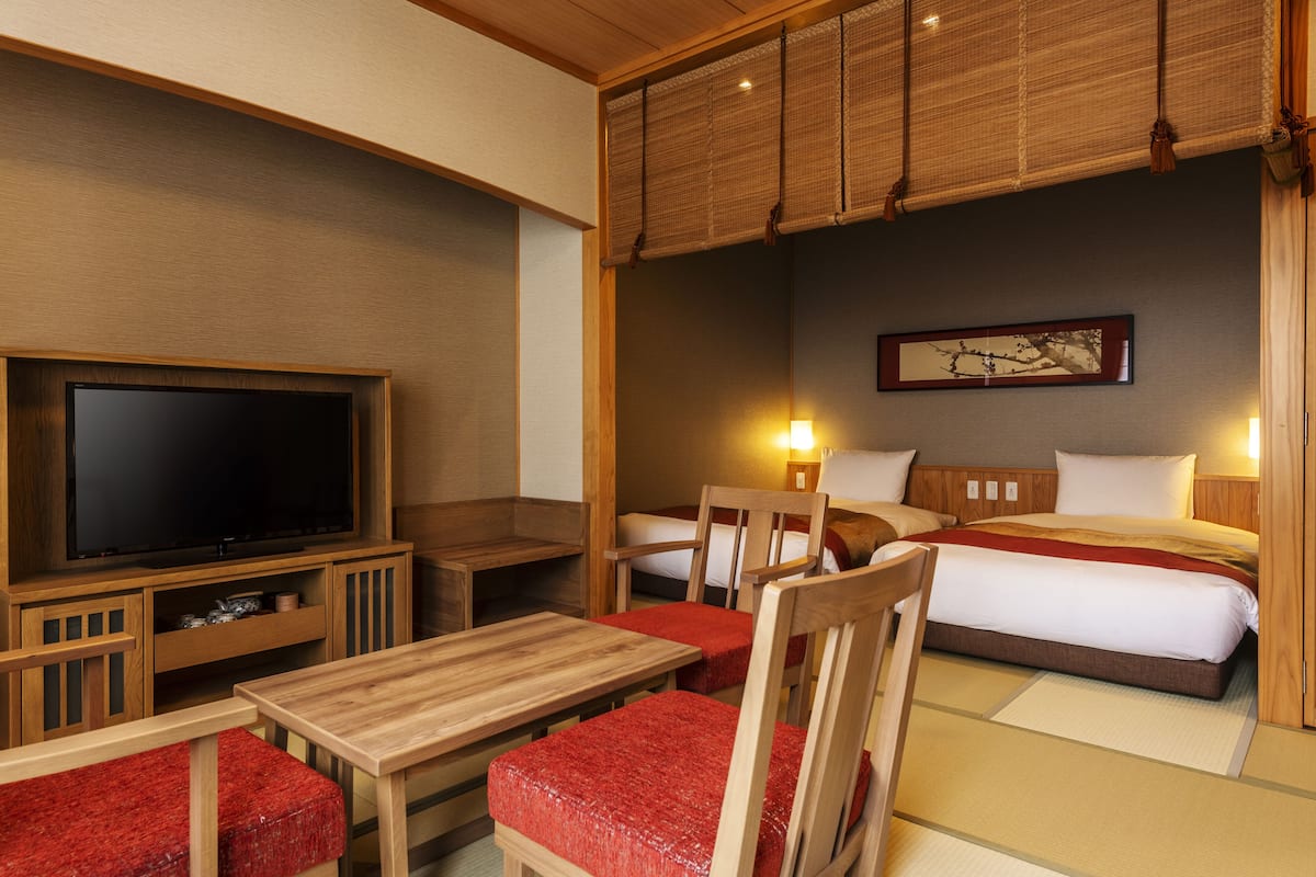 A traditional Japanese-style room with a television, wooden furniture, a bed, and a painting on the wall.