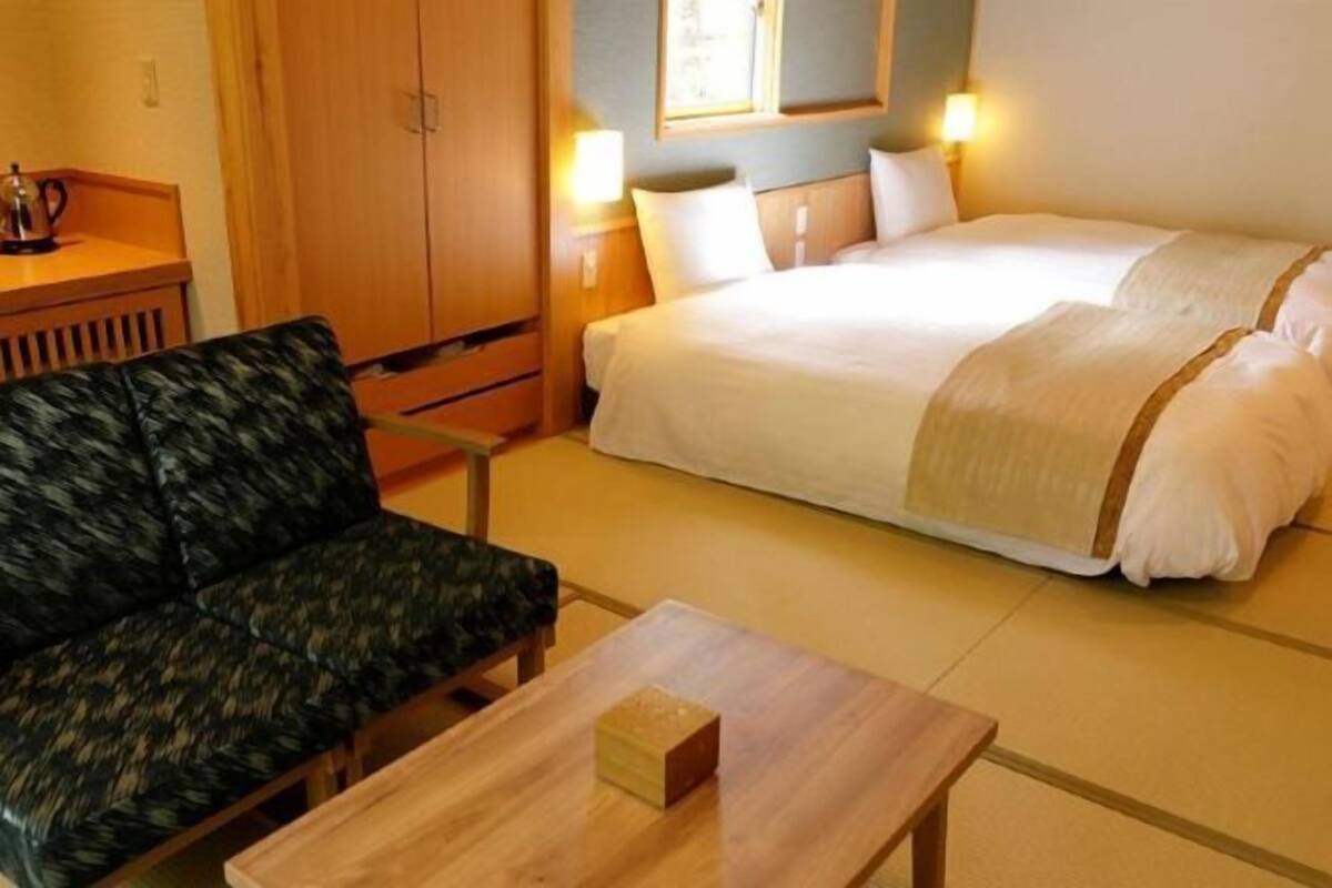 A hotel room with a bed, a sofa, a table, and a cabinet.