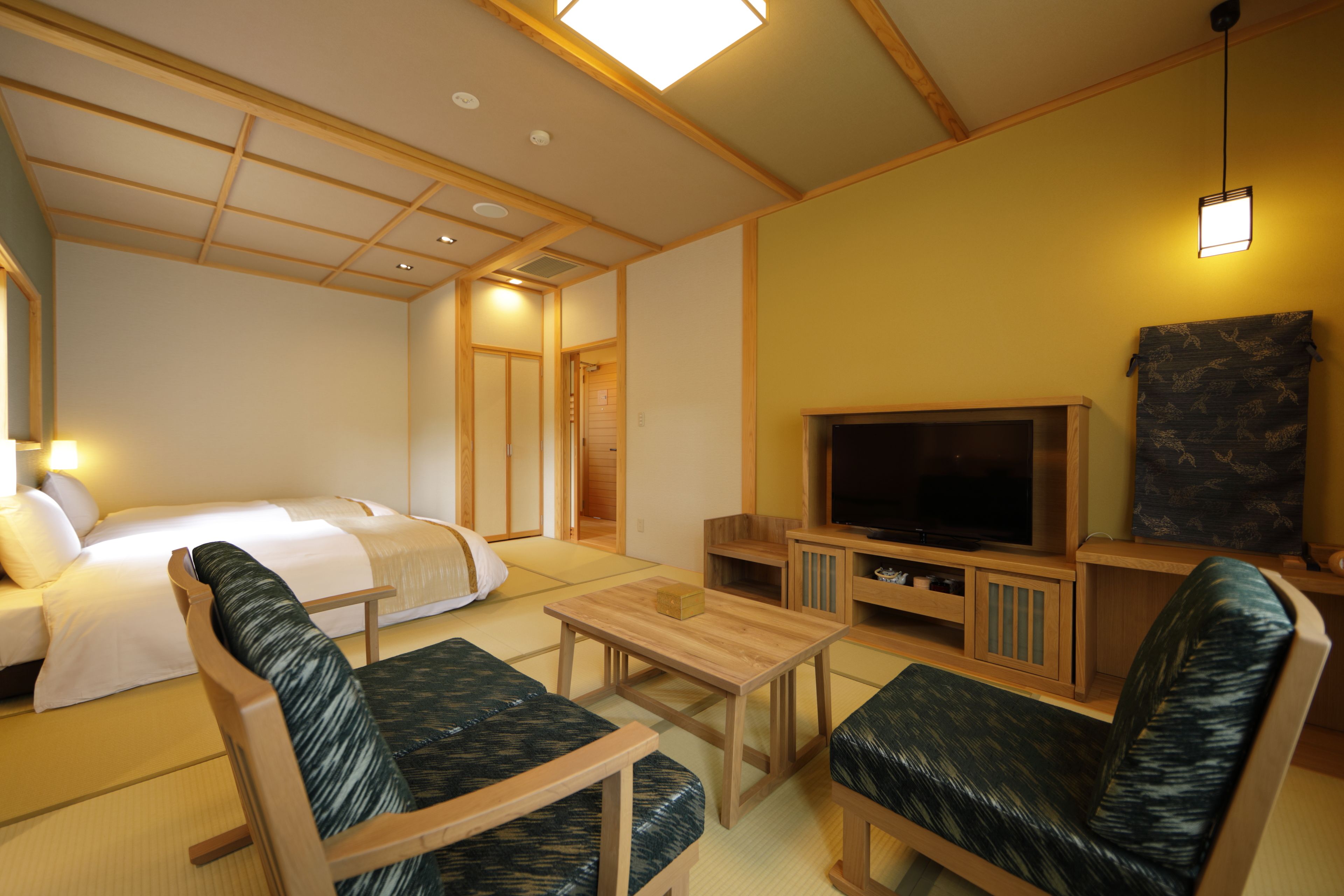 Una habitación tradicional japonesa con suelo de tatami, una cama con ropa de cama blanca, un televisor y muebles de madera.