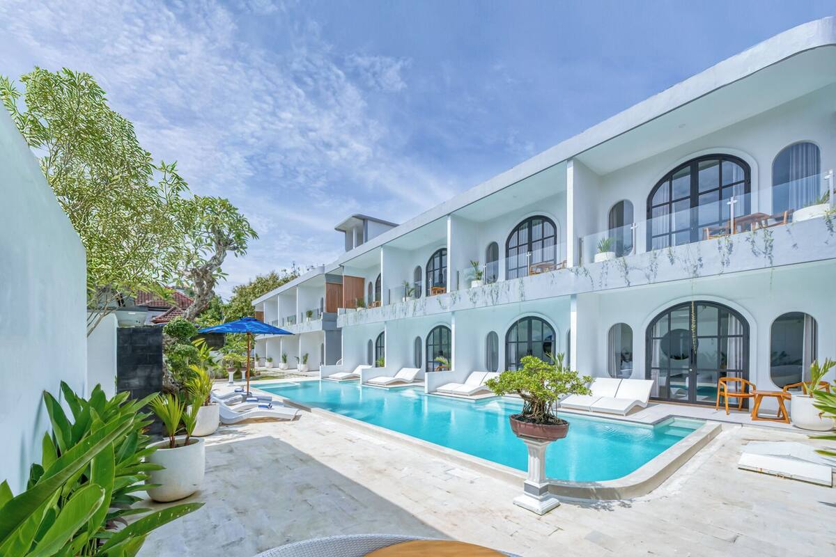 A modern hotel with a pool, outdoor seating, and a two-story structure with large windows.