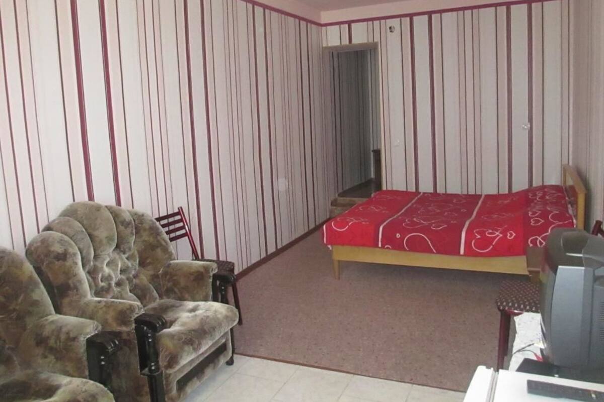 Un dormitorio con cama, sofá, televisión y puerta que da a otra habitación.