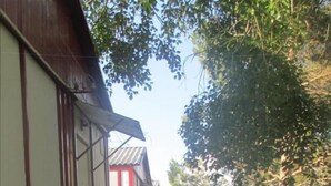 Ein schmaler Betonweg, gesäumt von Gebäuden mit rot-weiß gestreiften Markisen, führt zu einer kleinen Struktur mit Stufen.