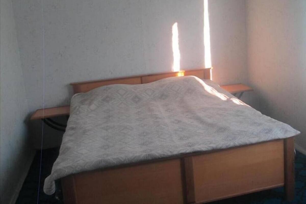 Una cama individual con cabecera de madera y una colcha estampada.