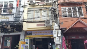 Un edificio con varios pisos, balcones y un letrero de 'CatBa-WithLocals' que ofrece servicios de viaje.